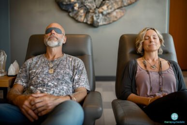 Deux personnes, un homme et une femme, en méditation profonde ou en état de relaxation durant une séance de thérapie psychédélique. L'homme porte des lunettes de soleil opaques. La scène évoque la contemplation intérieure et la guidance en thérapie assistée.